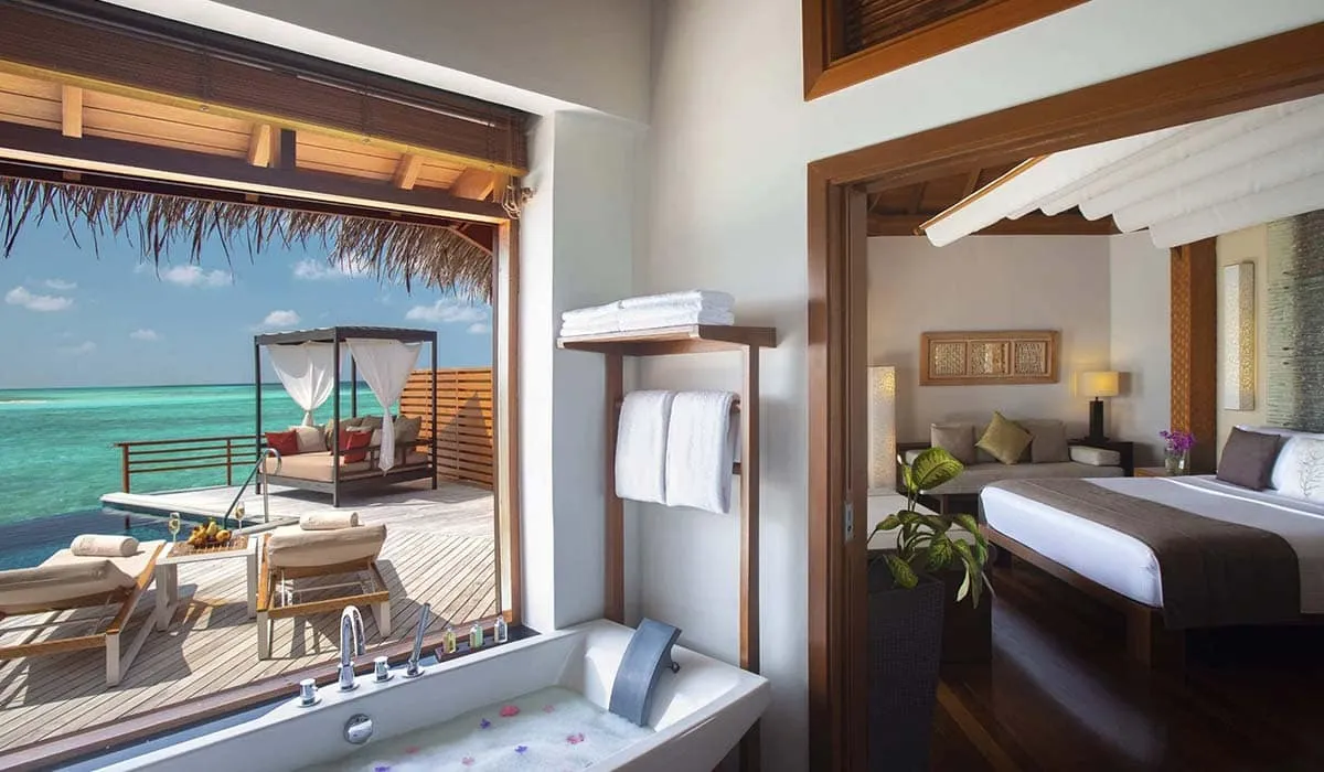 Water villa bathtub opening onto the bedroom and a sea-view pool deck