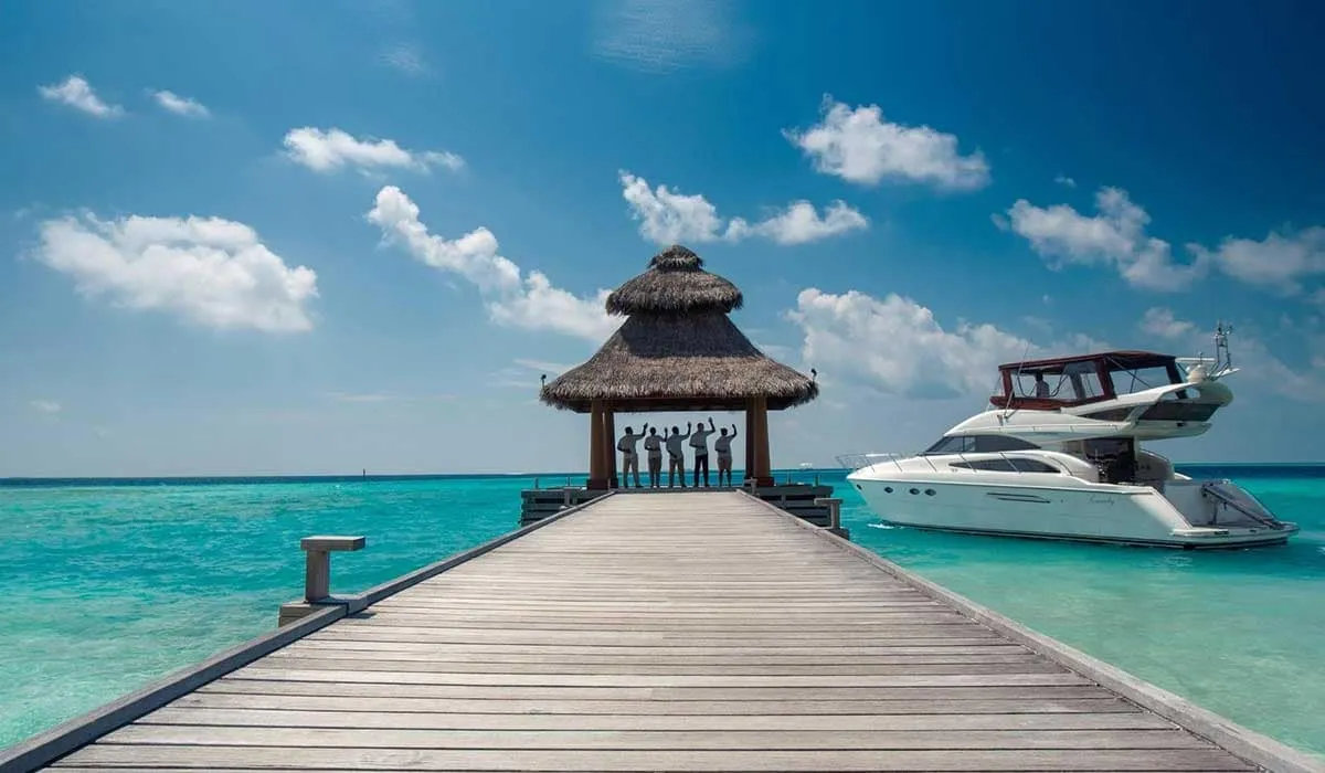 Wooden jetty leading to a thatched pavilion, with a yacht moored alongside