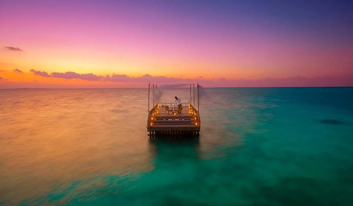 Candlelit pavilion on stilts in the lagoon at sunset