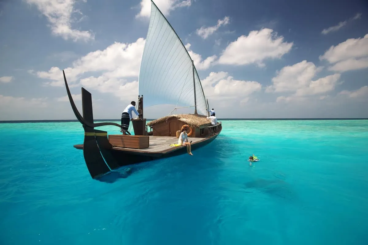 Traditional sailing boat on turquoise water with a snorkeller alongside