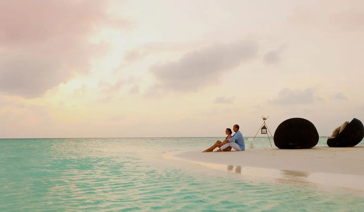 Couple sitting together on a sandbank at the water's edge