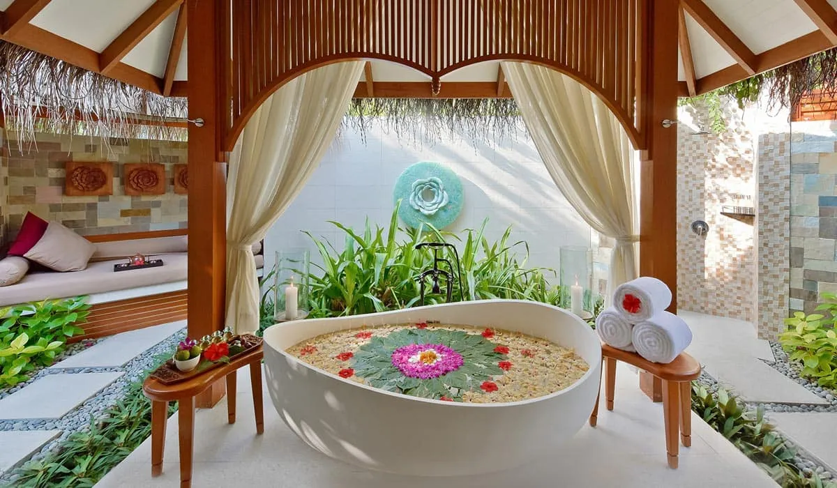 Flower-petal bath in an open-air spa pavilion framed by curtains
