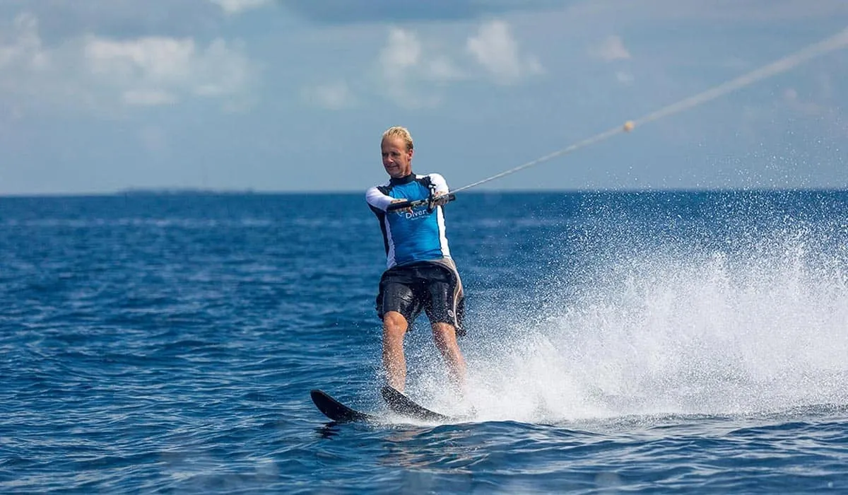 Man waterskiing across the blue sea, throwing up spray