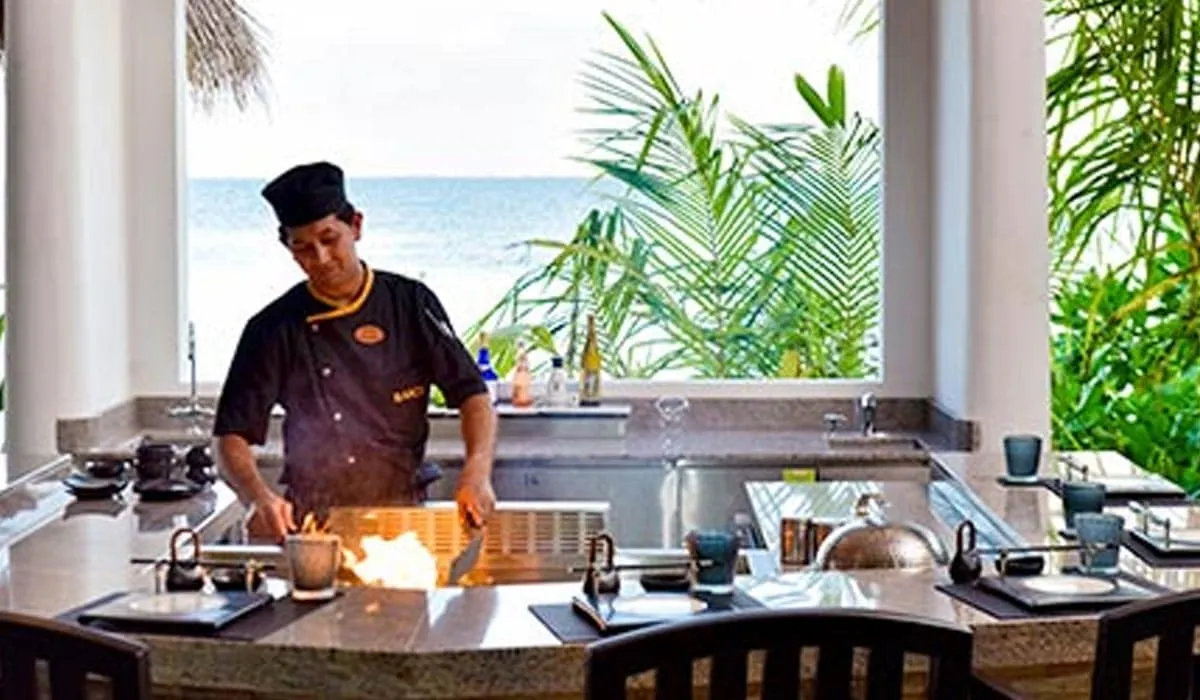Chef cooking at a teppanyaki grill in an open-air restaurant