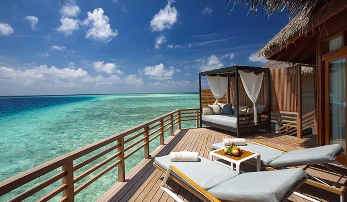 Water villa deck with loungers and a curtained daybed over the lagoon