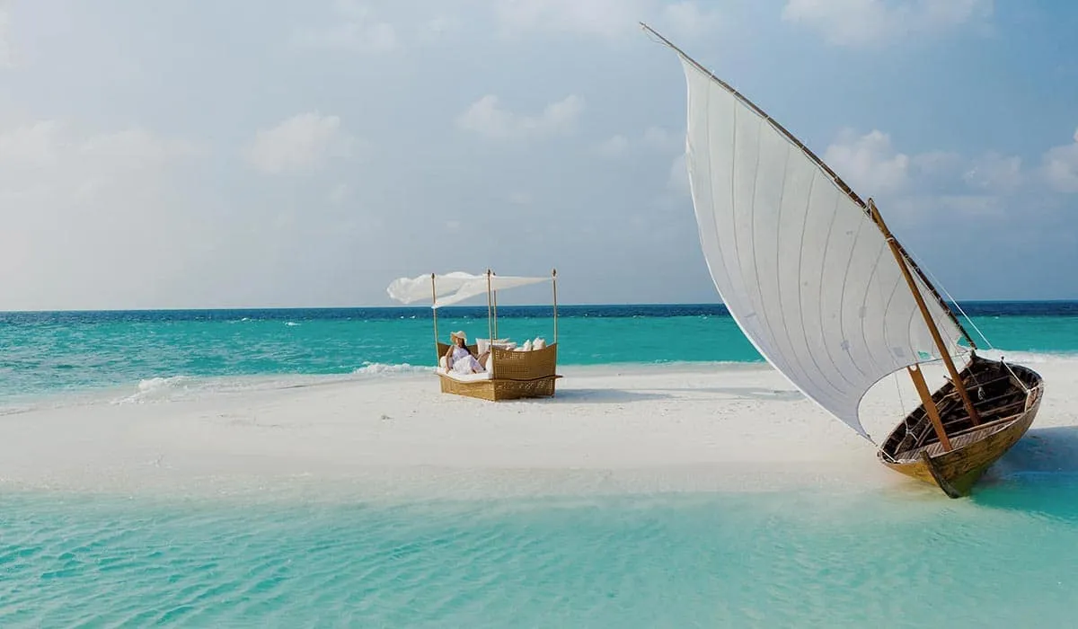 Sandbank picnic with a canopy daybed and a traditional sailing boat on the sand