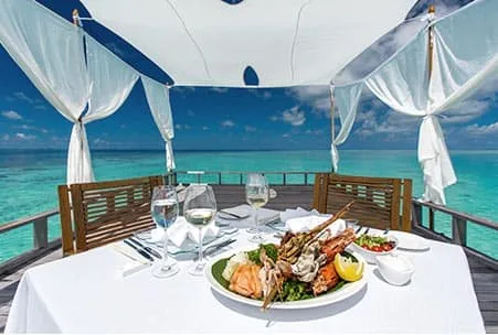 Seafood platter on a white table under a canopy overlooking the sea