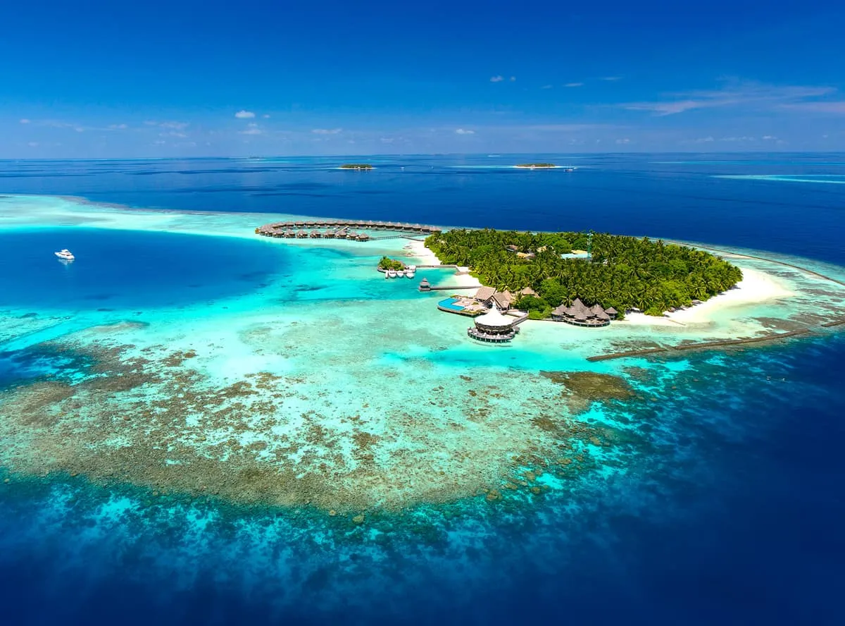 Aerial view of Baros island and its water villas, ringed by coral reef