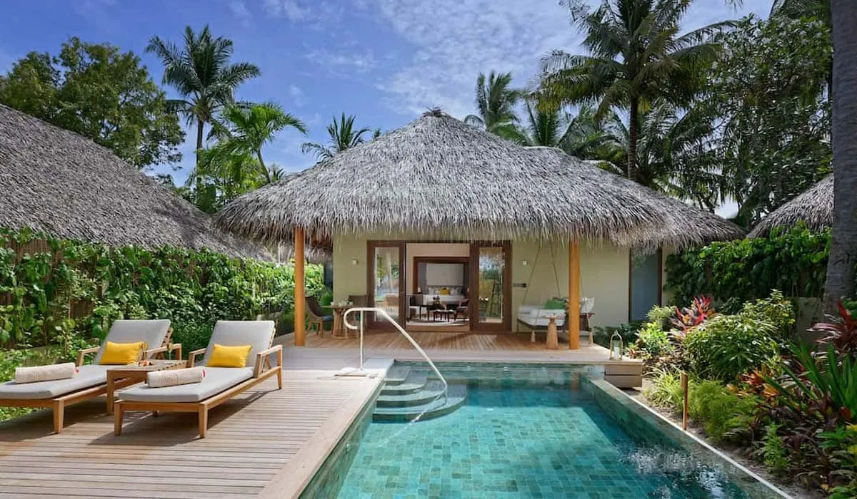 Thatched villa with sun loungers and a private pool among palm trees
