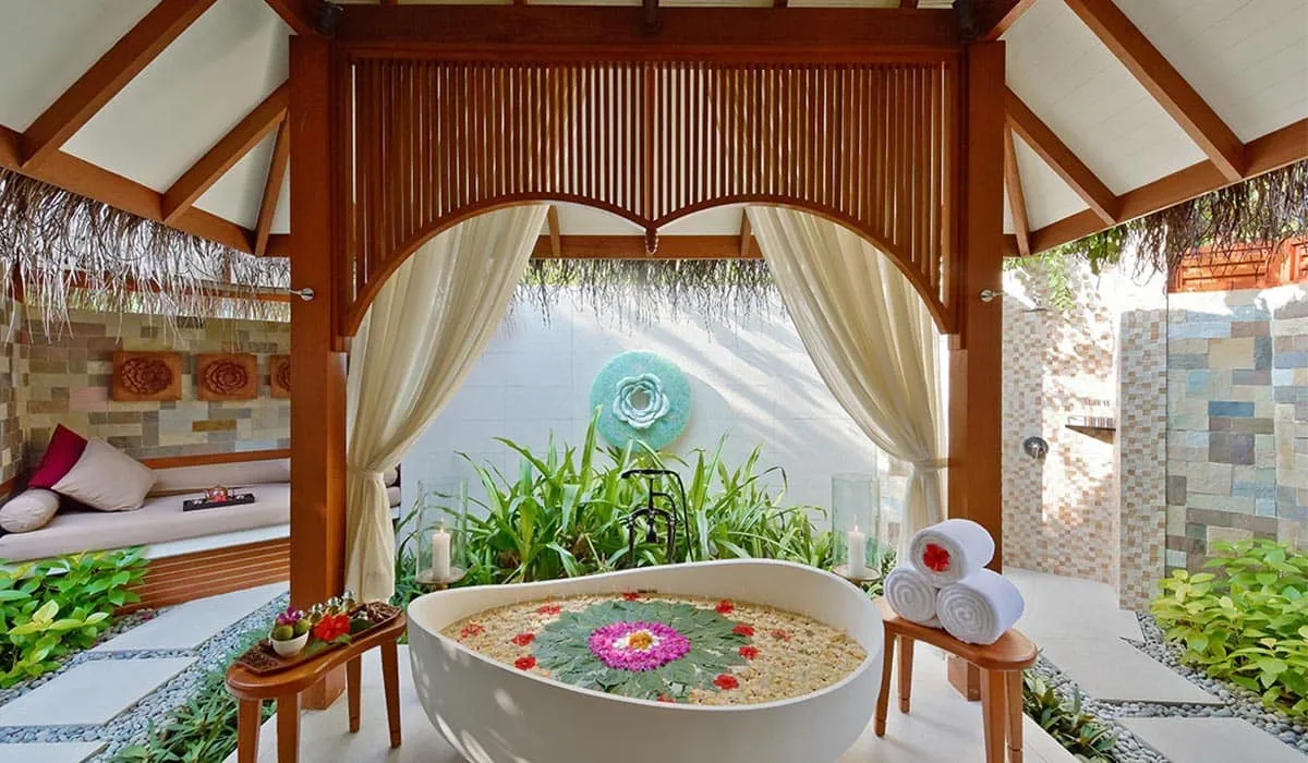 Flower-petal bath in an open-air spa pavilion framed by curtains