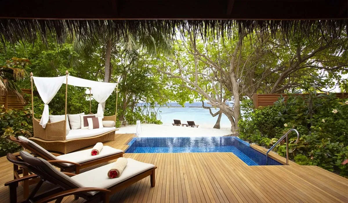 Beach villa deck with a canopy daybed, loungers and private pool facing the sea