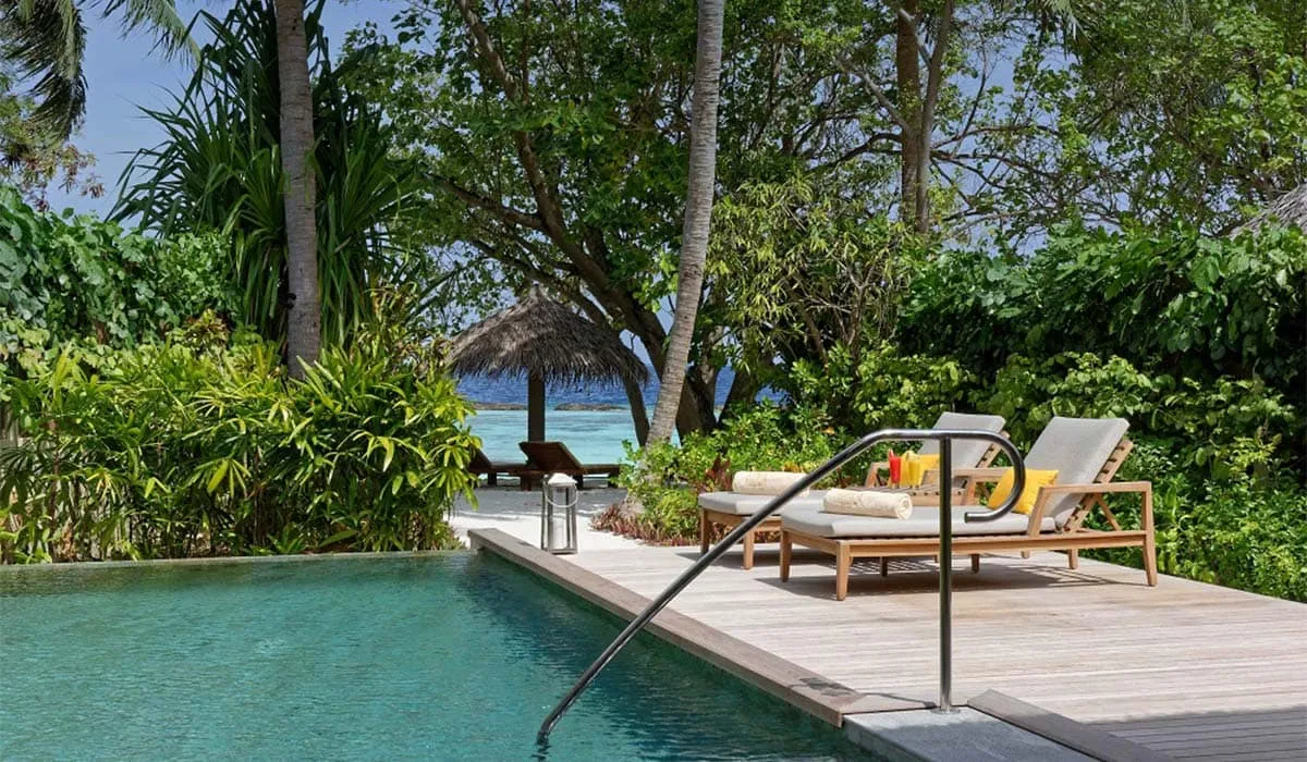Private pool and sun loungers on a villa deck surrounded by tropical greenery