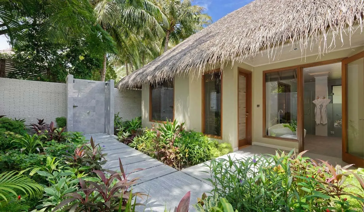 Thatched beach villa with a garden path and outdoor shower