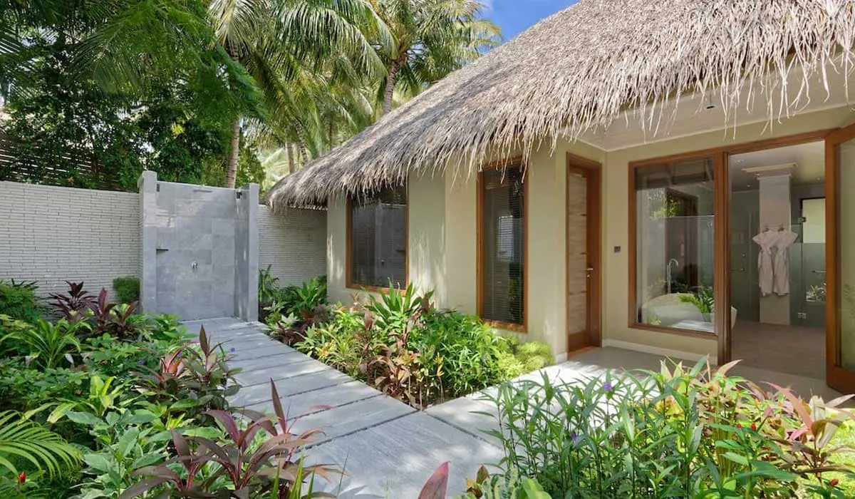 Thatched beach villa with a garden path and walled outdoor shower