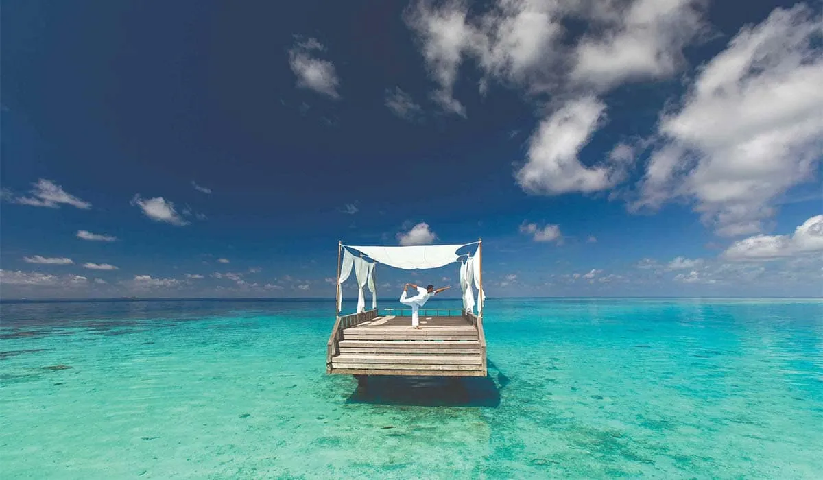 Couple relaxing under a canopy on a floating deck in the turquoise lagoon