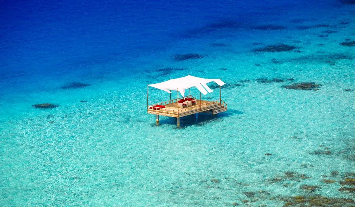 Aerial view of a floating deck set with a picnic in turquoise water