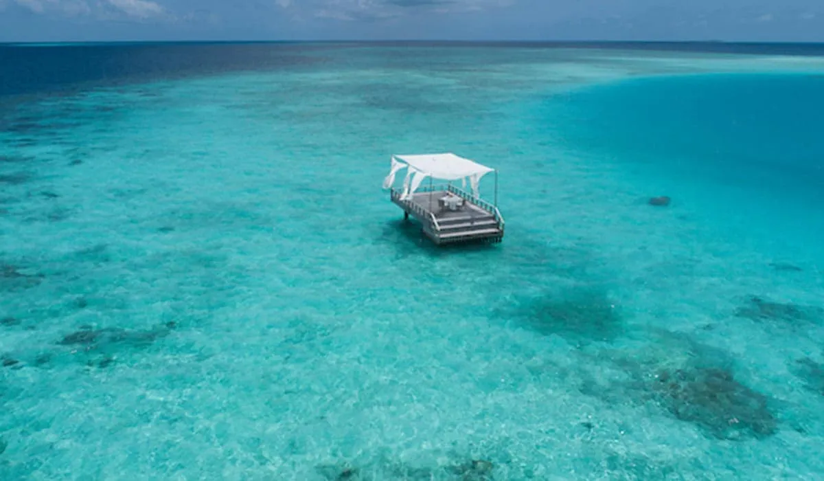 Canopied floating deck anchored in a turquoise lagoon, seen from above