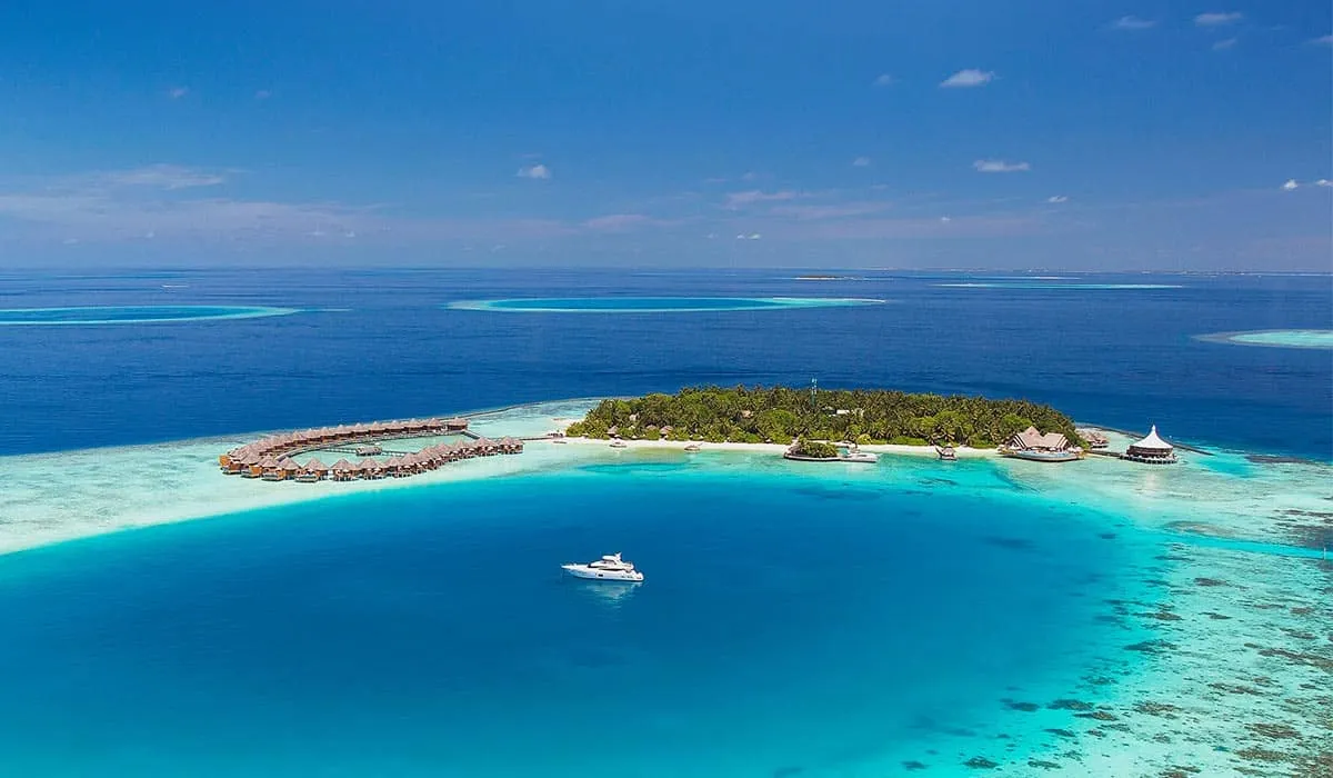 Aerial view of Baros island and water villas, with a yacht in the lagoon
