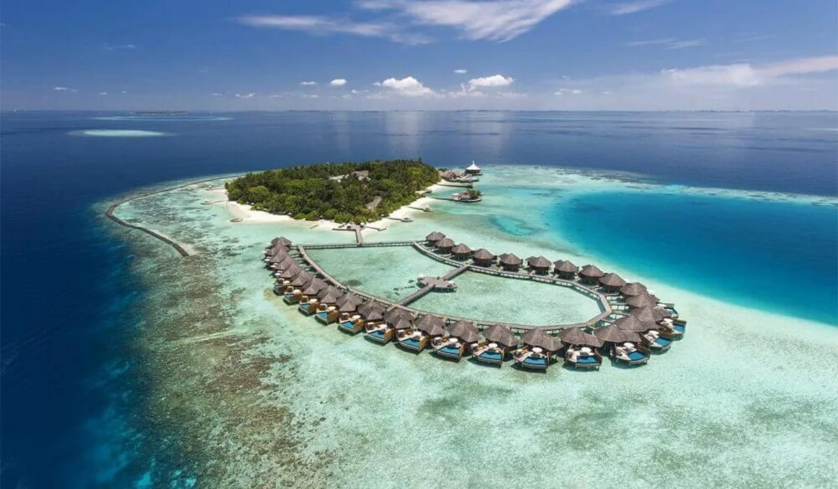 Aerial view of Baros island and its oval of water villas in turquoise sea