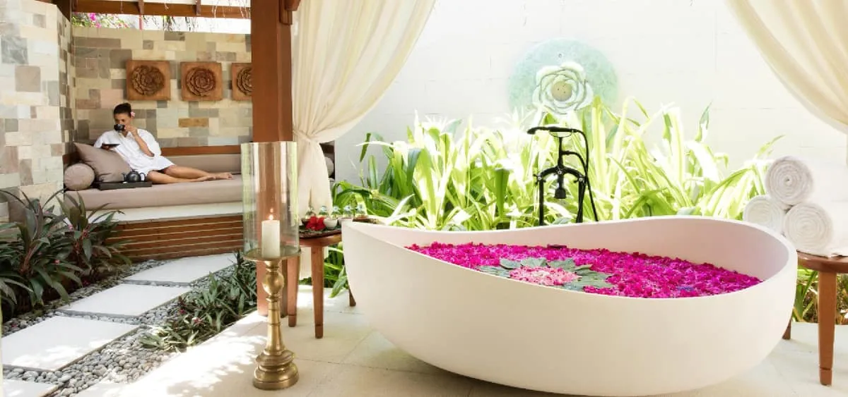 Guest reclining in an open-air spa pavilion beside a flower-petal bath