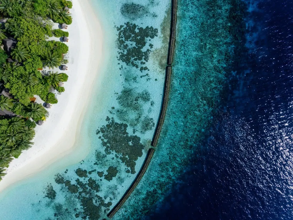 Aerial view of a white sand beach, shallow lagoon and deep blue reef edge