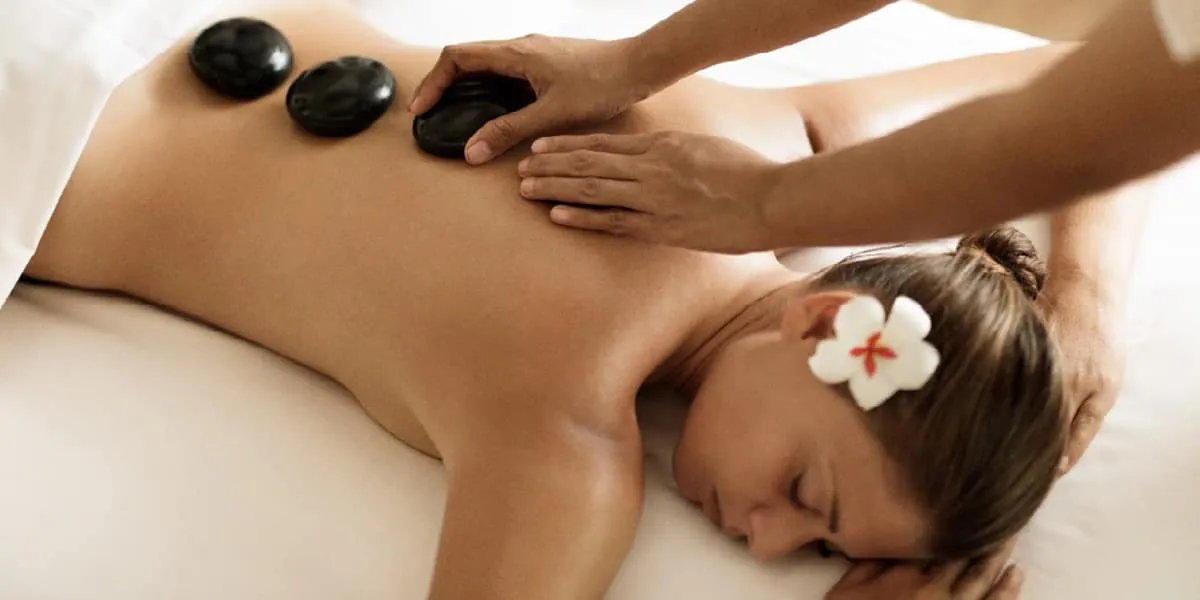 Woman receiving a hot stone massage with a flower in her hair