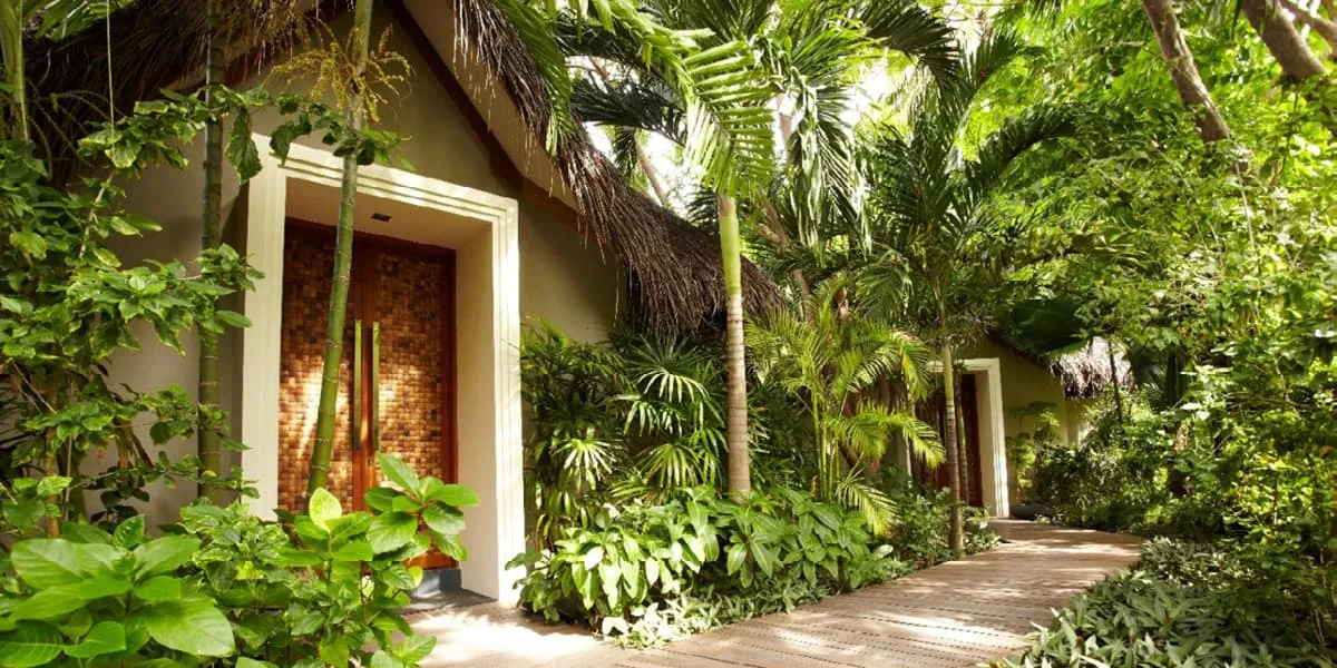 Carved wooden spa entrance surrounded by lush tropical plants