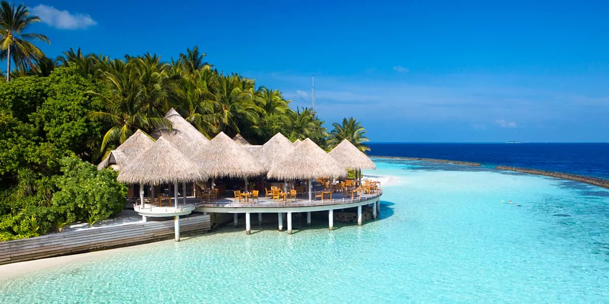 Thatched overwater restaurant above a bright turquoise lagoon