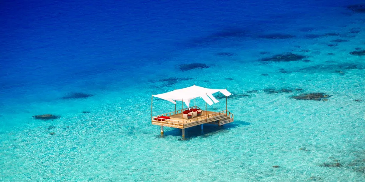 Canopied deck set for dining in the middle of a turquoise lagoon