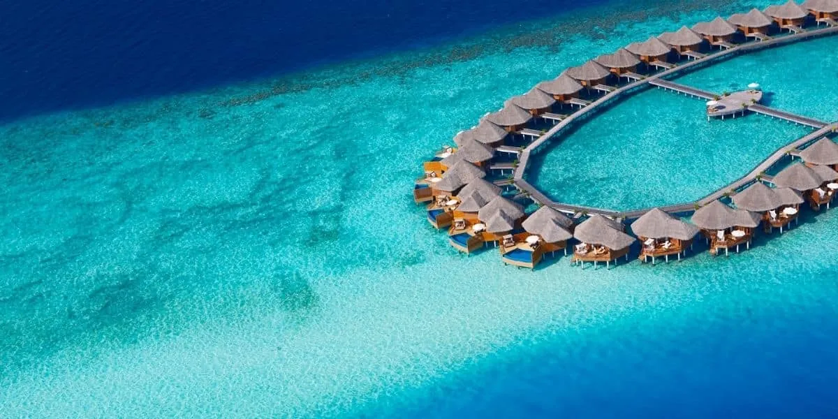 Aerial view of a horseshoe of water villas over a turquoise lagoon