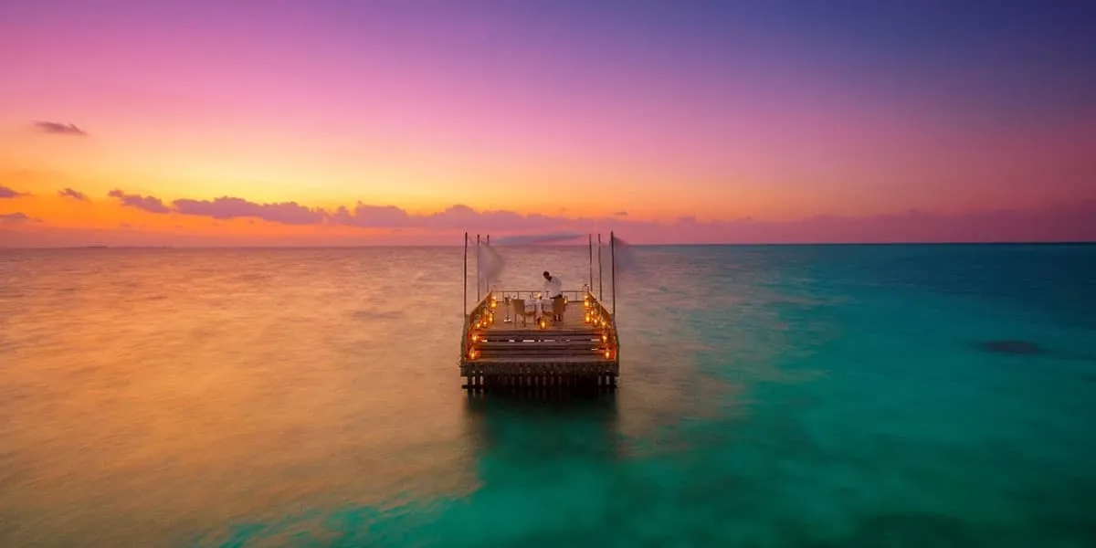 Canopied deck lit with candles in a calm lagoon at sunset