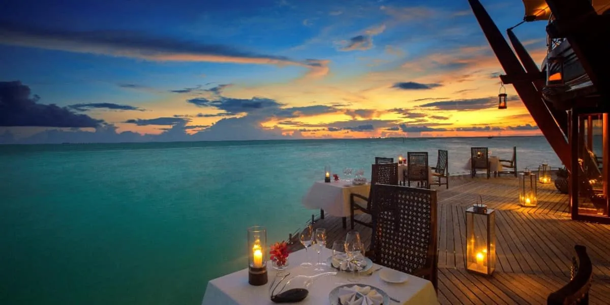 Candlelit tables on The Lighthouse Restaurant's overwater deck at dusk