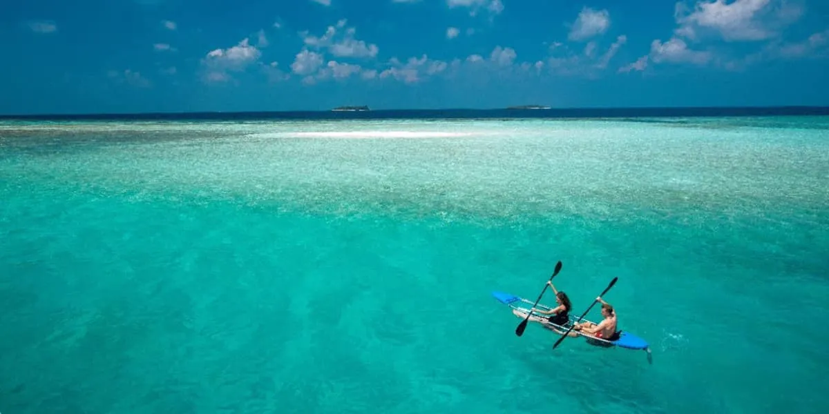 Two people paddling a kayak across a turquoise lagoon