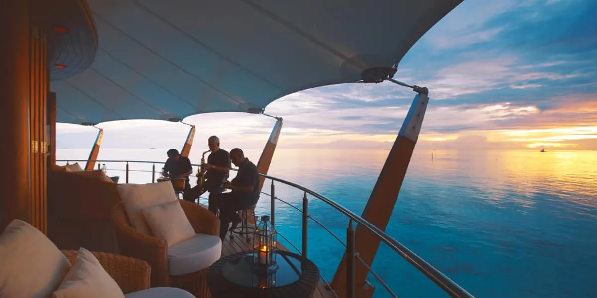 Guests at The Lighthouse lounge overlooking the sea at sunset