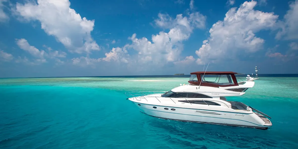 White motor yacht cruising across a turquoise lagoon