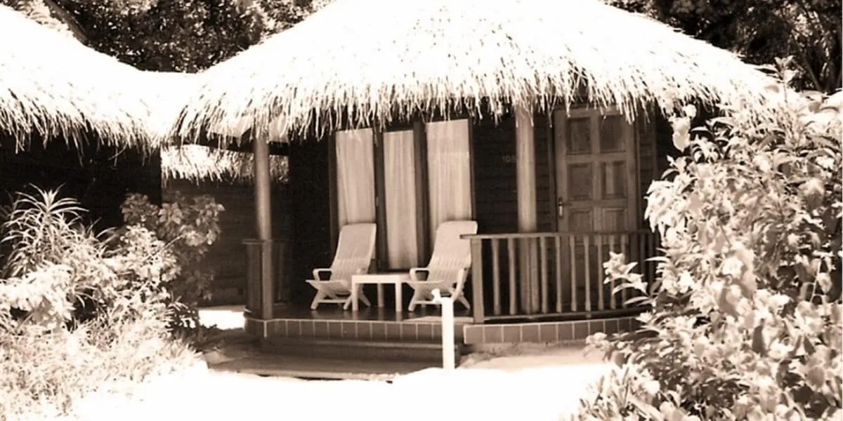 Archive sepia photo of a thatched bungalow with chairs on the veranda