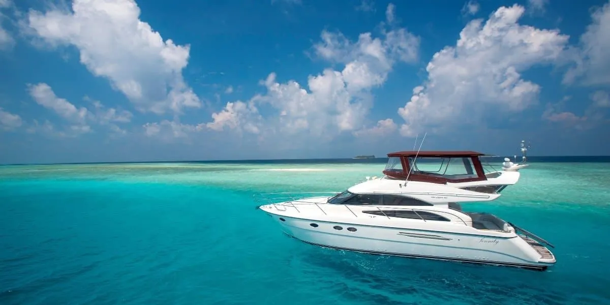 White motor yacht cruising across a turquoise lagoon