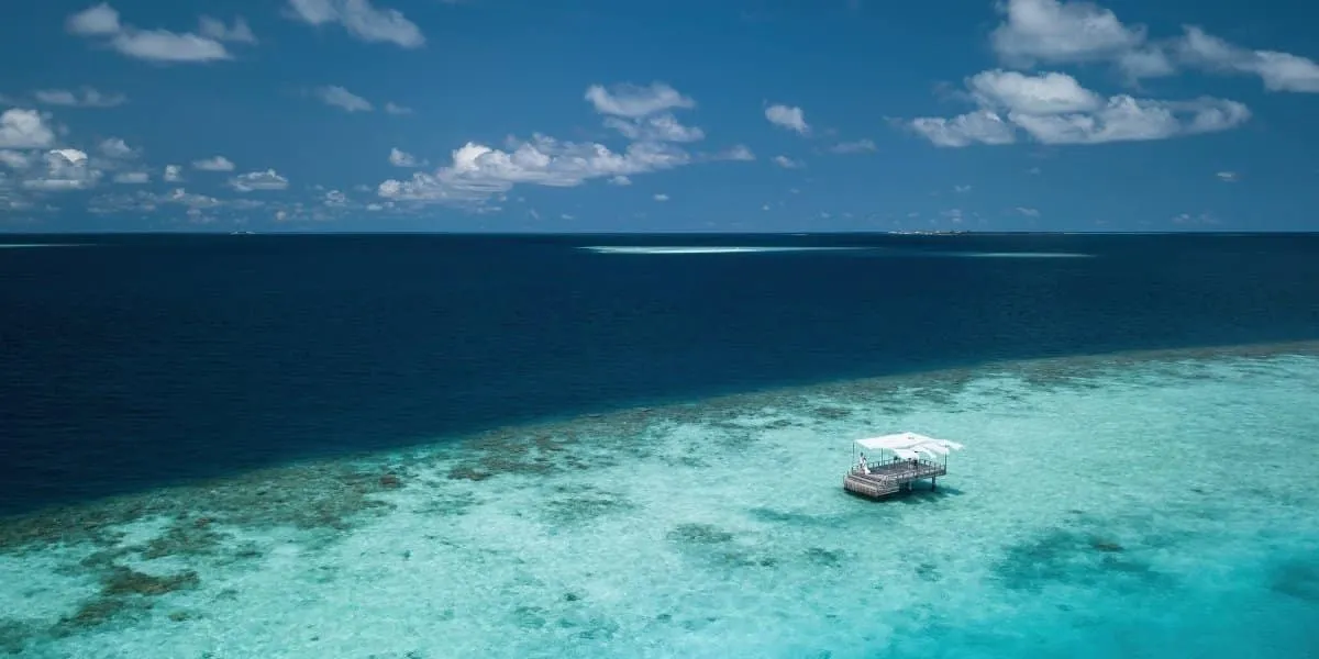 Canopied piano deck on the shallow reef beside deep blue ocean