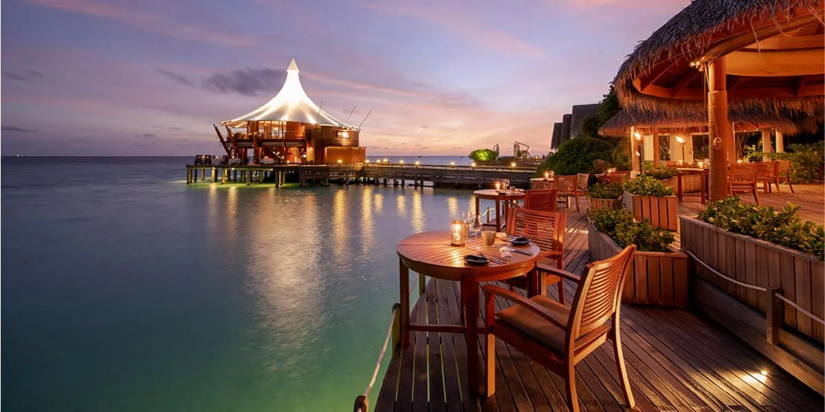 Restaurant deck lit at dusk with The Lighthouse in the distance