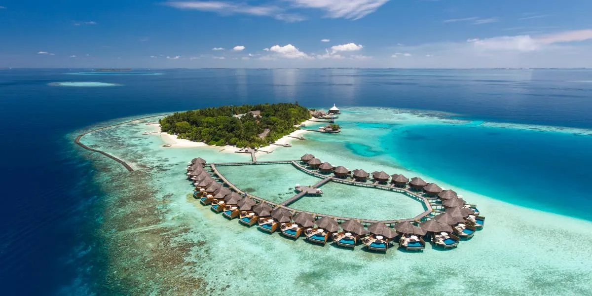 Aerial view of Baros island and its curve of water villas in a turquoise lagoon