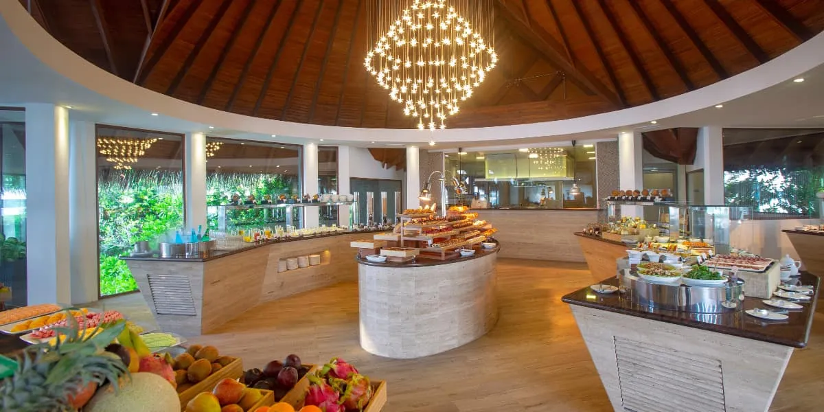 Buffet restaurant interior with a chandelier and displays of fresh fruit