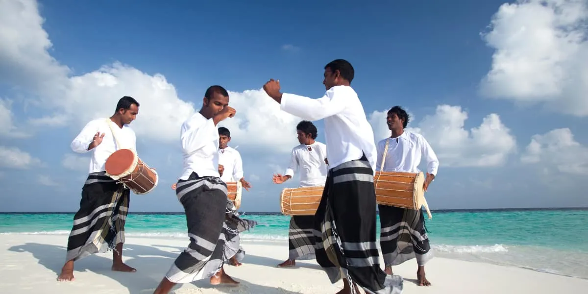 Drummers in traditional dress performing on a beach