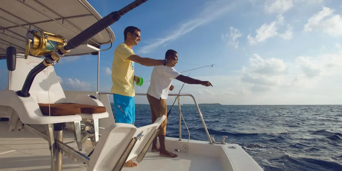 Two men fishing with rods from the deck of a boat