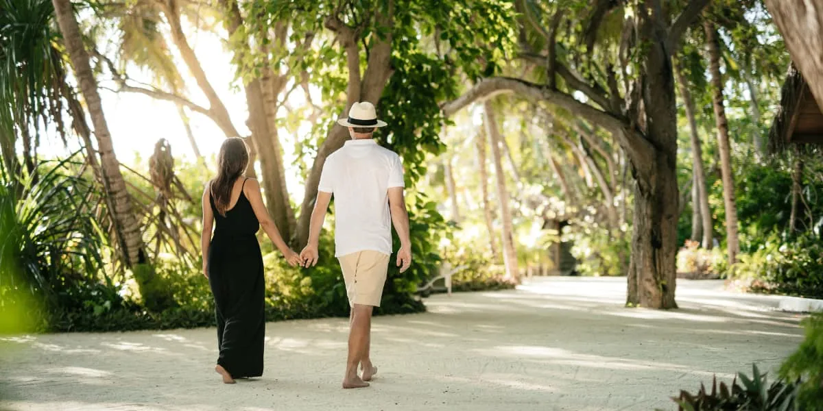 Couple walking hand in hand along a sandy garden path