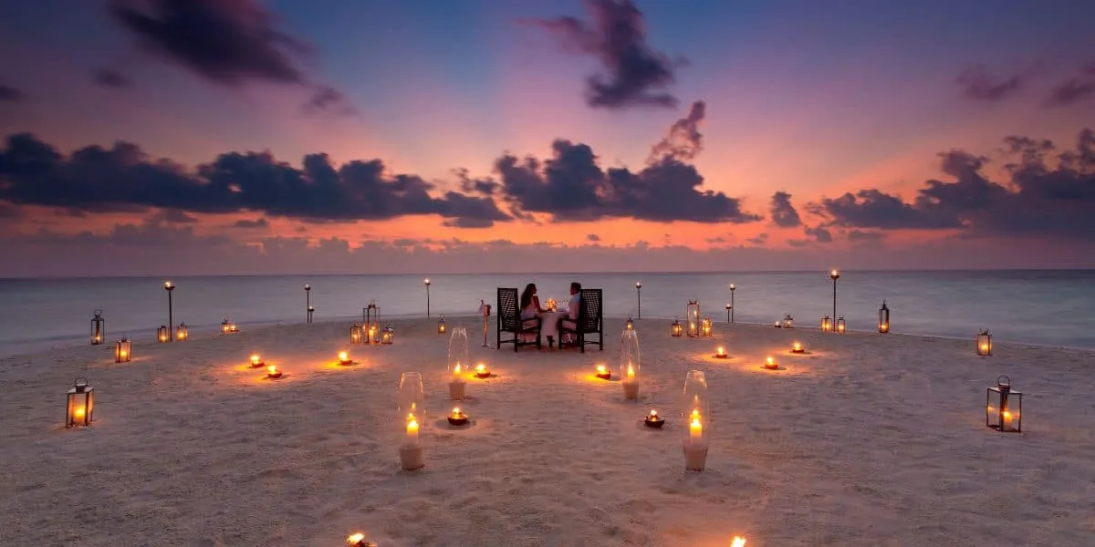 Candlelit dinner for two on the beach at dusk