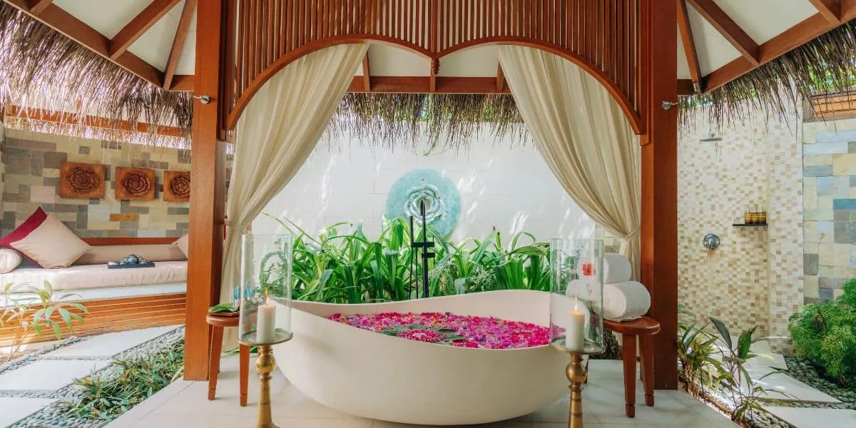 Petal-filled outdoor bath in a thatched pavilion