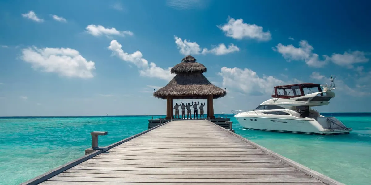 Wooden jetty leading to a thatched pavilion with a motor yacht moored alongside