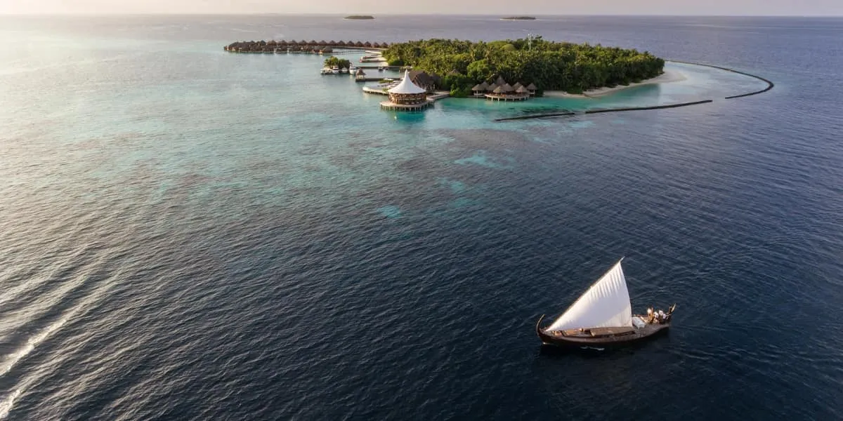 Aerial view of Baros island at dusk with a traditional dhoni sailing past