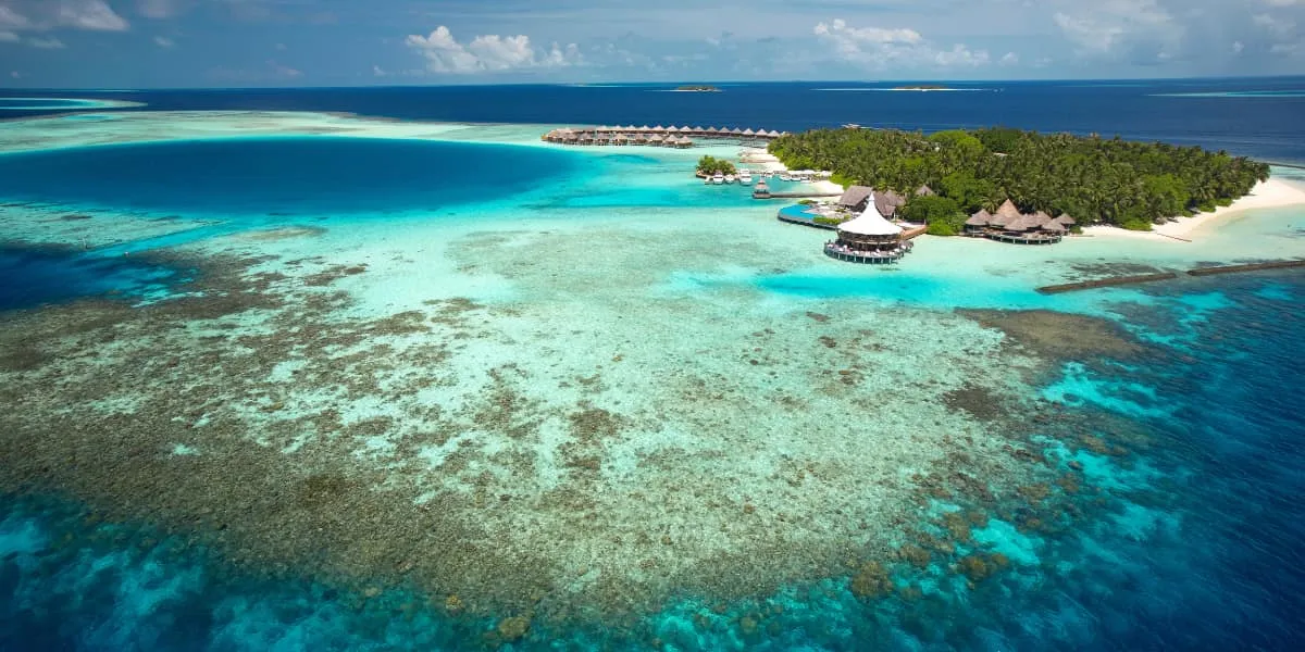 Aerial view of Baros island surrounded by a wide turquoise coral reef