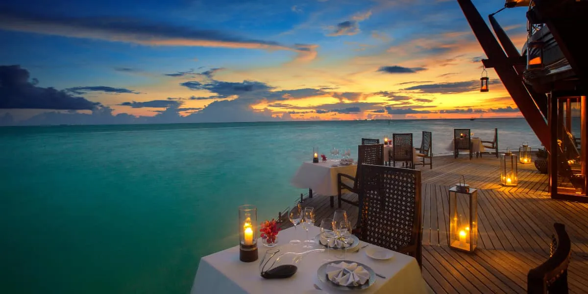 Candlelit dinner table on a wooden deck over the sea at sunset